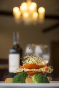 a plate with a sandwich on a table with a bottle of wine at Hotel Czerniewski in Warsaw
