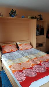 ブラウンラーゲにあるWohnen wie bei Freundenのベッド(オレンジ&白のシーツ、枕付)