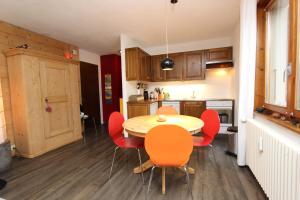 une cuisine avec une table et des chaises rouges dans l'établissement Les Erables, à Château-d'Oex