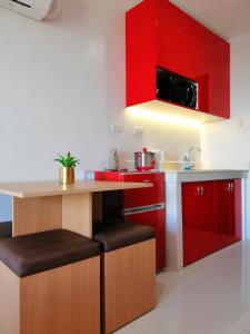 kuchnia z czerwonymi szafkami i blatem ze stołkami w obiekcie Cityscape Residences 1102 w mieście Bacolod
