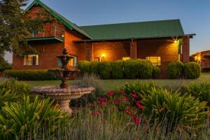 a house with a fountain in front of a yard at Olive Tree Farm in Magaliesburg