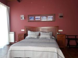 a bedroom with a bed with a red wall at Hotel Las Murallas in Ávila