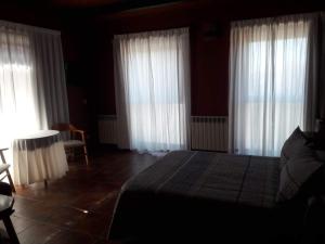 Hotel Las Murallas في أفيلا: غرفة نوم مع ستائر بيضاء وسرير وطاولة