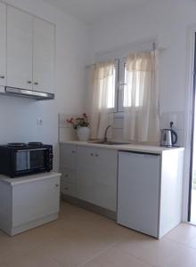 a white kitchen with a microwave and a sink at Kedraki in Kalamaki