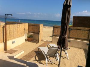un patio con 2 sillas y una sombrilla en la playa en Les Pieds dans l'Eau, en La Croix-Valmer