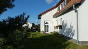 a white house with a window and a yard at Ferienwohnung 1, Neuendorf - Hiddensee in Neuendorf