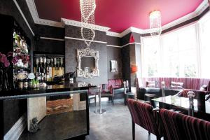a bar with pink walls and red chairs at Cotford Hotel in Great Malvern