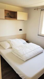 a large white bed in a room with a window at Mobilhome 2ch climatisé à la Palmyre in Les Mathes