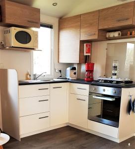 a kitchen with white cabinets and a stove top oven at Mobilhome 2ch climatisé à la Palmyre in Les Mathes