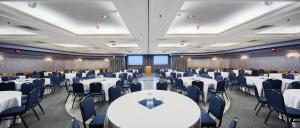 un salón de banquetes con mesas blancas y sillas azules en Norwood Hotel en Winnipeg