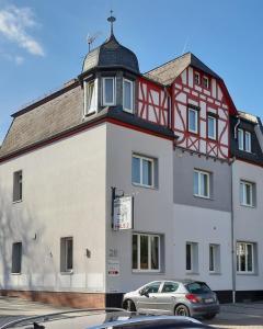 un bâtiment blanc et rouge avec une tour d'horloge dans l'établissement Hotel Sonne - Haus 2, à Idstein
