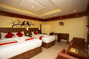 a hotel room with two beds and a table and a desk at Hotel Splendid View in Pokhara