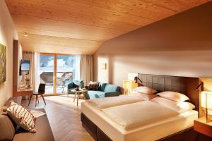 a bedroom with a large bed and a living room at Hotel die Wälderin-Wellness, Sport & Natur in Mellau