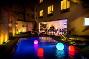 a pool with colorful lights in a courtyard at night at Elements Hotel Boutique in Managua