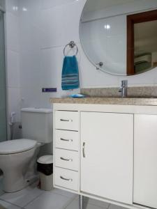 a bathroom with a toilet and a sink and a mirror at Apto Praia de Itapoã 2 qto c/ar in Vila Velha
