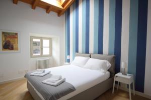 Schlafzimmer mit einem Bett mit blauen und weißen Streifen in der Unterkunft Verbania - Luxury Italy Apartments in Verbania