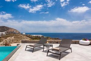 a patio with two chairs next to a swimming pool at Luxury Villa Artemis by Mykonos Luxury in Elia Beach