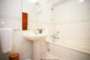a white bathroom with a sink and a bath tub at Sotto Mayor Residence in Figueira da Foz +37 photos