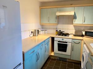 a kitchen with blue cabinets and a stove top oven at Cosy Corner House in Kettering
