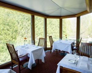jadalnia z białymi stołami, krzesłami i oknami w obiekcie Millcroft Inn & Spa w mieście Alton