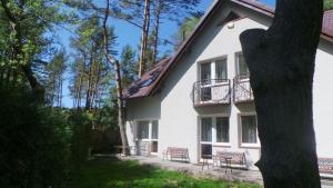 a white house with chairs and a balcony at Pokoje gościnne Żaczek in Dębki