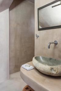 a bathroom with a stone sink and a mirror at Villa Apollo by Mykonos Luxury in Elia Beach