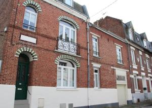 un edificio de ladrillo rojo con una puerta verde y ventanas en Le Kooka, en Arras