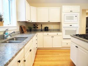 a white kitchen with white cabinets and a sink at Modern House Family Retreat in Bar Harbor