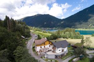 una vista aerea di una casa con lago e montagne di Pension Mitterer a Weissensee