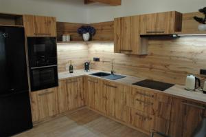 uma cozinha com armários de madeira e um frigorífico preto em Village Romantic Apartment by Český Krumlov - adults only em Střížov
