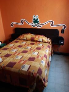 a bed in a bedroom with an orange wall at Hotel Recreo in Mexico City