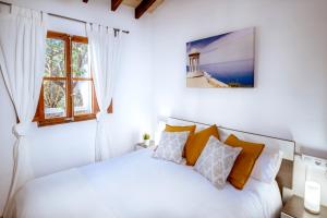 a white bedroom with a bed and a window at Villa Ca'n Verd in Alcudia