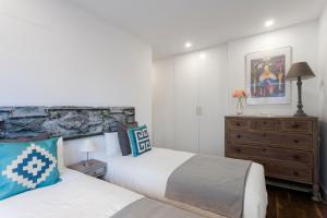 a bedroom with two beds and a dresser at dobohomes - Fernando el Católico in Madrid