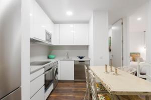 a kitchen with white cabinets and a table with chairs at dobohomes - Fernando el Católico in Madrid