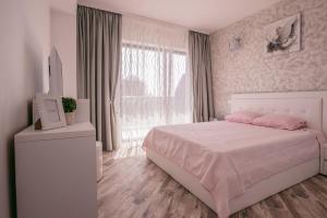 - une chambre blanche avec un lit rose et une fenêtre dans l'établissement Apartamente MRM Residence, à Mamaia Nord – Năvodari