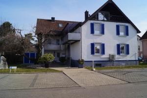 una casa blanca con persianas azules en una calle en Residenz Labee en Weil am Rhein