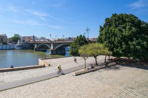a group of people sitting on benches next to a river at AlohaMundi Almansa in Seville