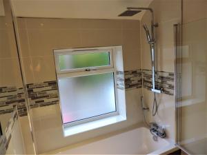 a bathroom with a window above a bath tub at 3 Bed Farnborough Air Accommodation in Farnborough +23 photos
