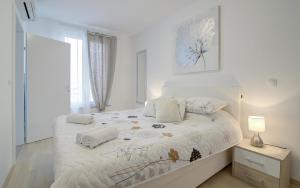 a white bedroom with a bed with two pillows at Apartments Luka - Villa Sunce in Senj