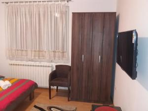 a bedroom with a large wooden cabinet and a chair at Apartman Donji Kraj in Cetinje