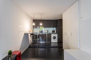 a kitchen with white cabinets and a washer and dryer at FLH Studio Alfama in Lisbon