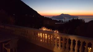 a sunset behind a fence with a mountain in the background at Il Profumo di Capri in Massa Lubrense
