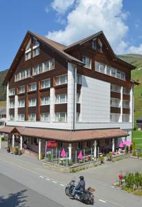a man riding a motorcycle in front of a building at Hotel Piz Badus in Andermatt