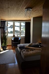 Hotel Piz Badus في أندرمات: غرفة نوم بسرير وكرسي ونوافذ