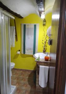 Baño amarillo con lavabo y aseo en Vivelorural, en Cuevas Labradas