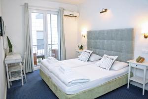 sypialnia z dużym białym łóżkiem i balkonem w obiekcie Hotel Delfin w mieście Zadar +37 zdjęć