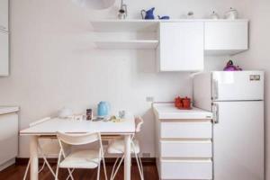 ボローニャにあるwhouse suite porta di castelloの白いキッチン(テーブル、冷蔵庫付)