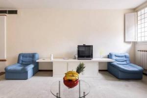 ボローニャにあるwhouse suite porta di castelloの青い椅子2脚、テーブル、テレビが備わる客室です。