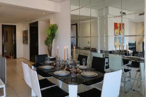 Sweet Jacob's Appartment Gueliz City Center في مراكش: غرفة طعام مع طاولة سوداء وكراسي بيضاء