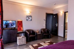 a room with a bed and chairs and a television at Vila Ana in Băile Govora